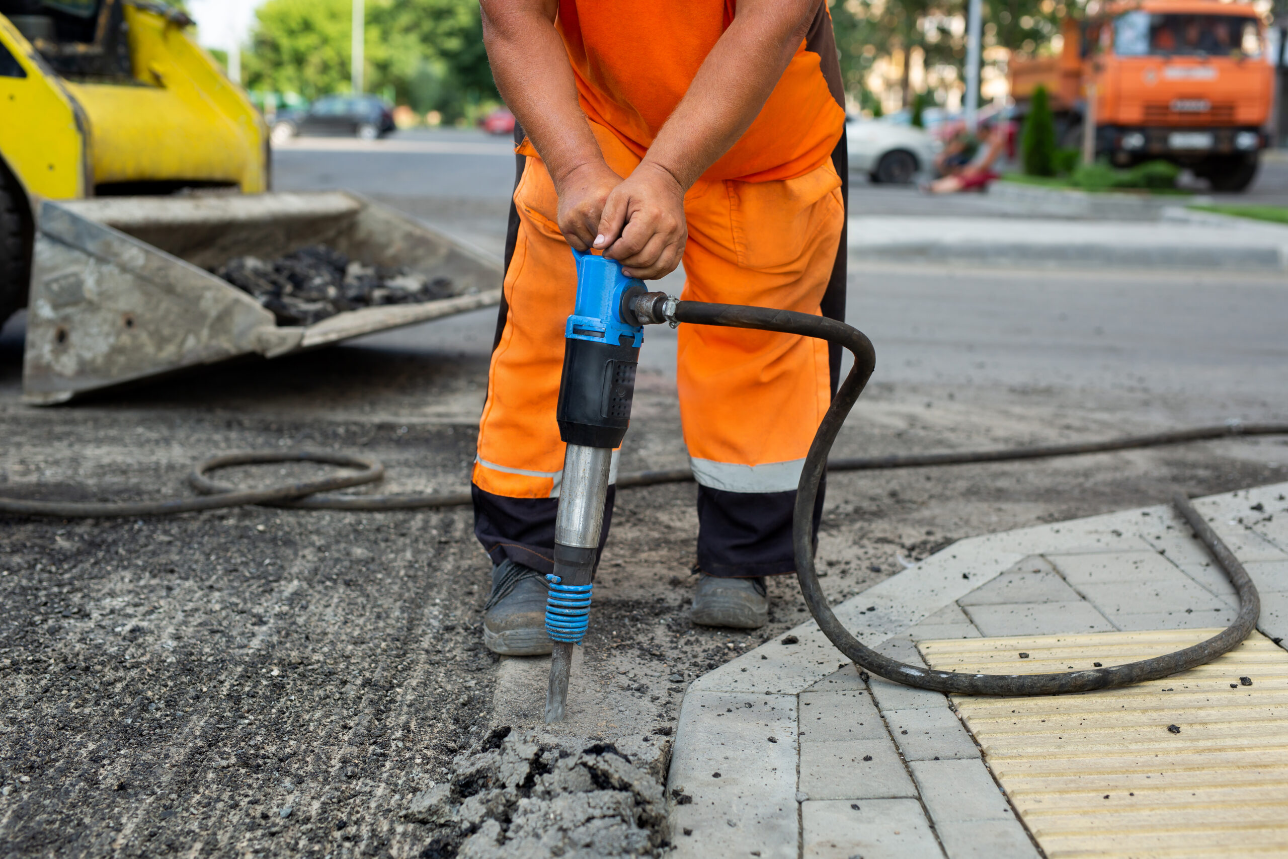 Road worker breaking street asphalt with jackhammer